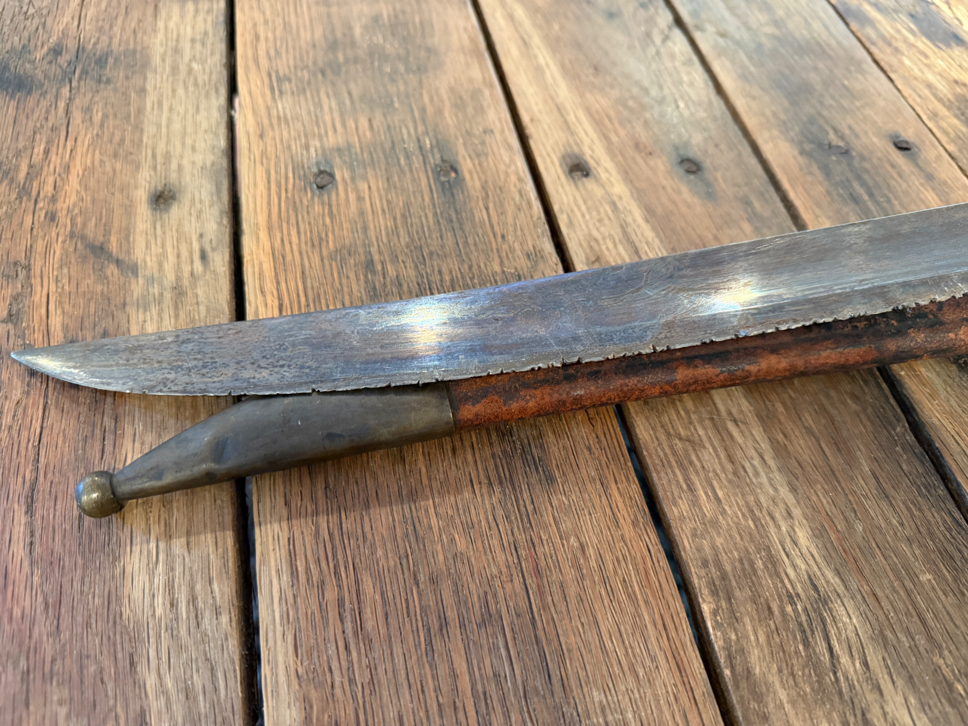 The cutlass blade tip beside the brass scabbard chape